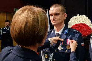 Przedstawicielka Wojewody dolnośląskiego przypina medal policjantowi.