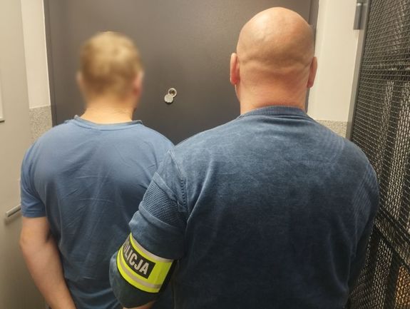 Policjant prowadzi zatrzymanego mężczyznę