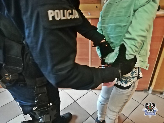 Policjant w mundurze zakłada kajdanki osobie zatrzymanej