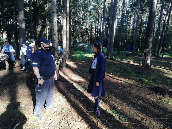 na zdjęciu widać policjanta umundurowanego rozmawiającego z obozowiczami.