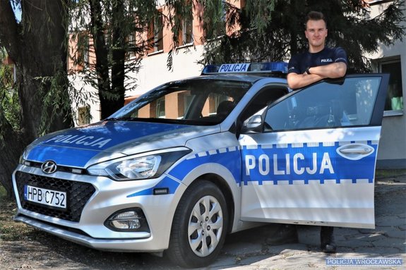 Wrocławski policjant stoi przy radiowozie