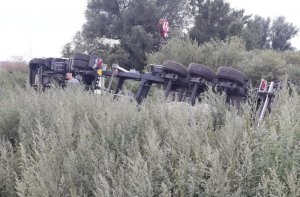 Na zdjęciu przewrócony na bok ciągnik siodłowy wraz z naczepą który osunął się do rowu, co spowodowało wywrócenie całego składu - widok z tyłu.