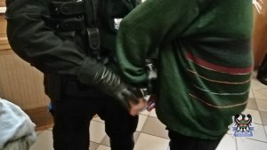 Na zdjęciu policjant zakłada kajdanki zatrzymanemu mężczyźnie.