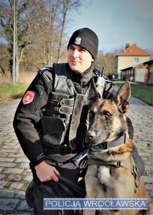 Zdjęcie przedstawia psa służbowego Lonara wraz ze swoim przewodnikiem.