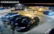obraz z kamery monitoringu na którym widać złodzieja udajacego się do zaparkowanego na światłach auta