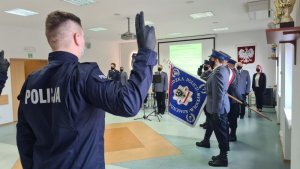 Na zdjęciu policjant podczas ślubowania w tle I Zastępca Komendanta Wojewódzkiego Policji inspektor Krzysztof Noculak wraz z naczelnikiem Wydziału Prezydialnego KWP we Wrocławiu, Godło Polski wiszące na ścianie w sali odpraw oraz poczet sztandarowy.