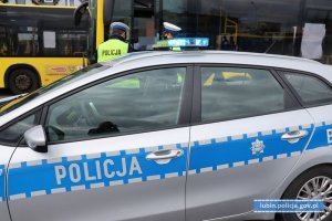 Na zdjęciu widać policjanta kontrolującego kierowcę autokaru, widać też radiowóz policyjny i autobus