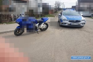 Na zdjęciu widać radiowóz policyjny i zatrzymany motocykl