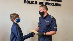 Z-ca komendanta Wojewódzkiego Policji we Wrocławiu wręcza dyplom chłopakowi
