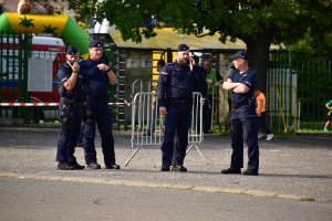 5- zdjęcie kolorowe: czterech umundurowanych policjantów przed stadionem GKS  Katowice