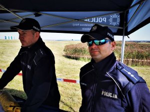 dwóch dzielnicowych pod namiotem profilaktycznym, jeden z nich ma założone okulary przeciwsłoneczne