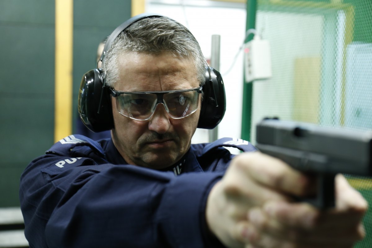 Policjant strzela do tarczy z broni ostrej.