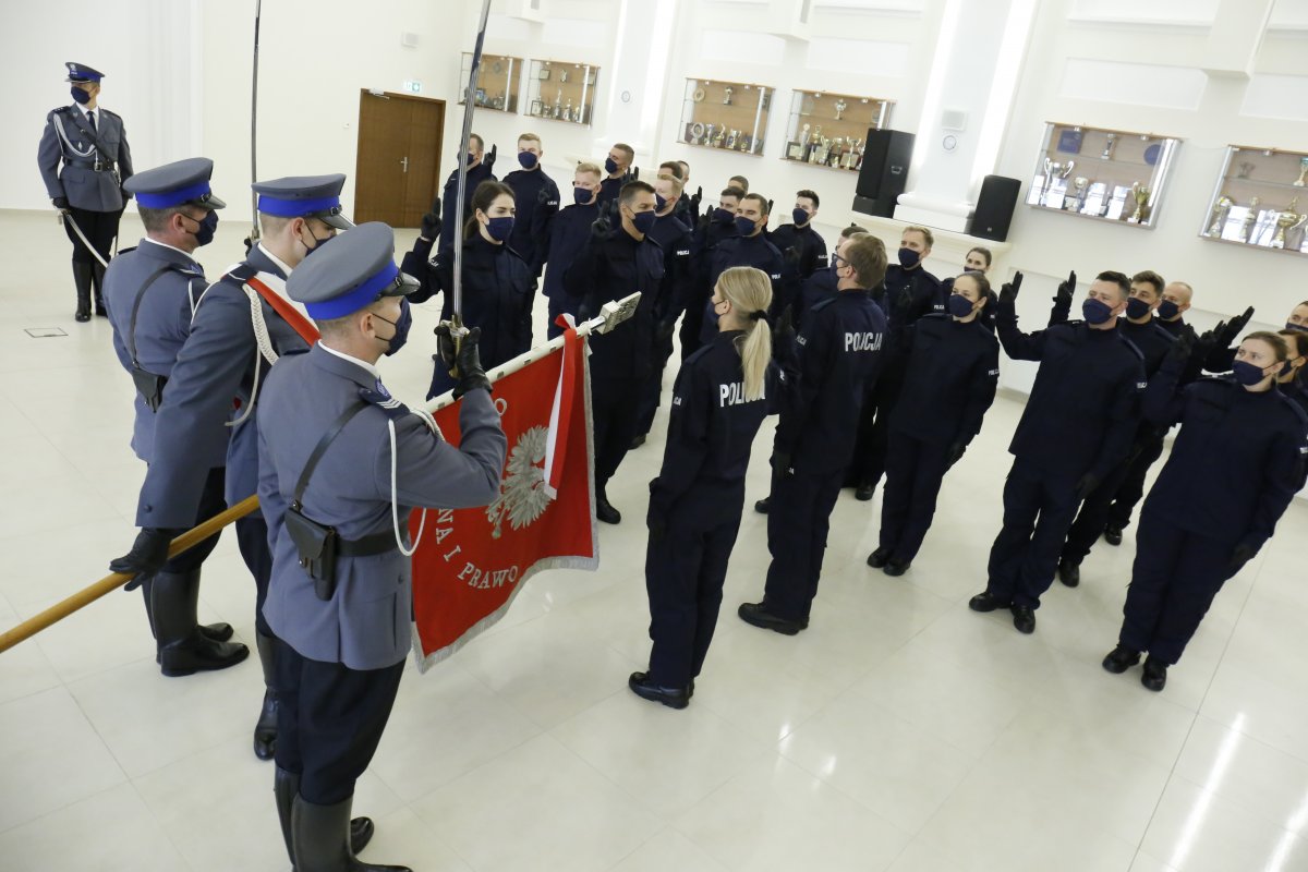 W pierwszym planie zdjęcia po lewej stronie widzimy trzech funkcjonariuszy pocztu sztandarowego, w drugim planie zdjęcia widzimy nowych funkcjonariuszy ślubujących na Sztandar