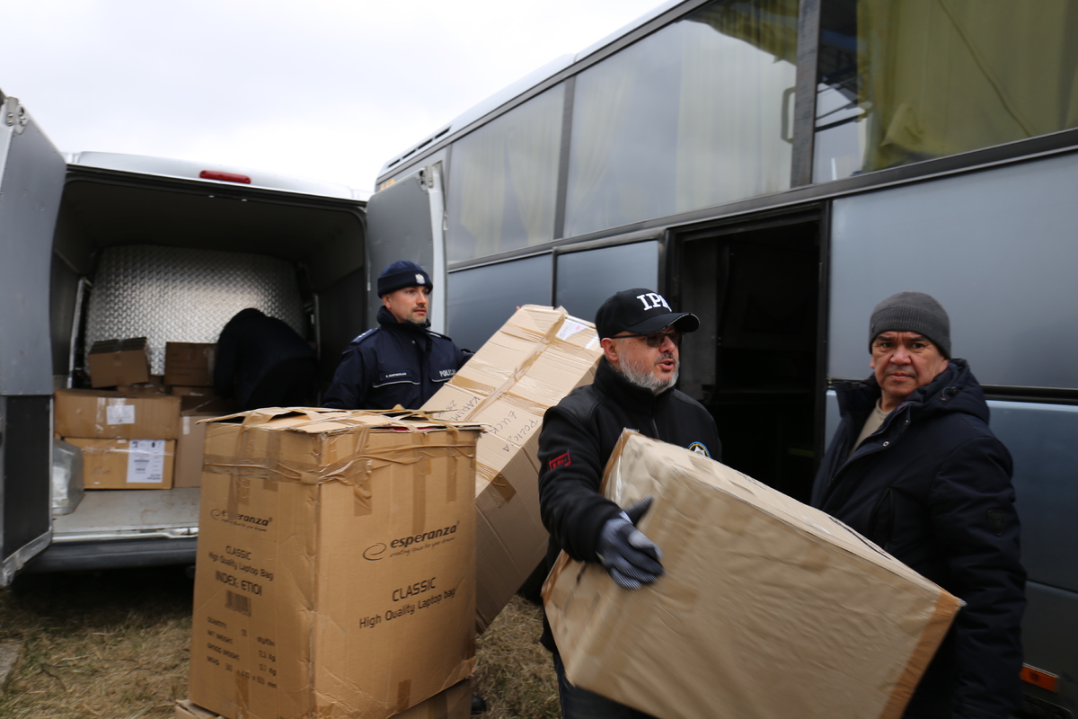 Policjanci przenoszą dary z busa do autokaru.