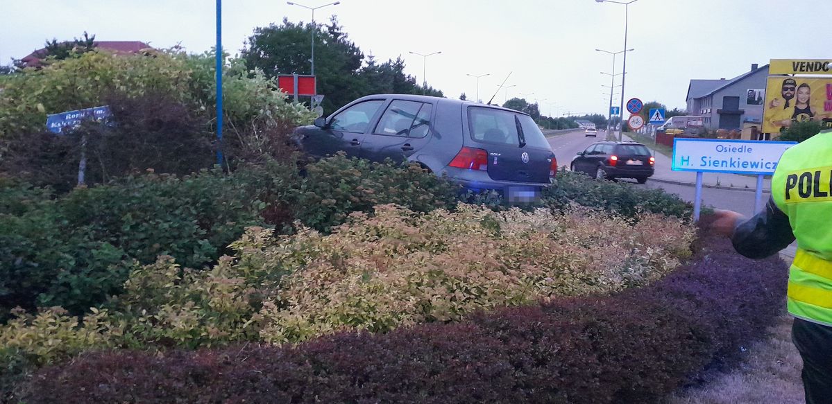 samochód marki Volkswagen Golf na środku ronda obok policjant