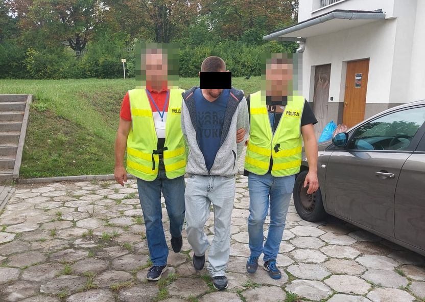 Policjanci prowadzą zatrzymanego mężczyznę.