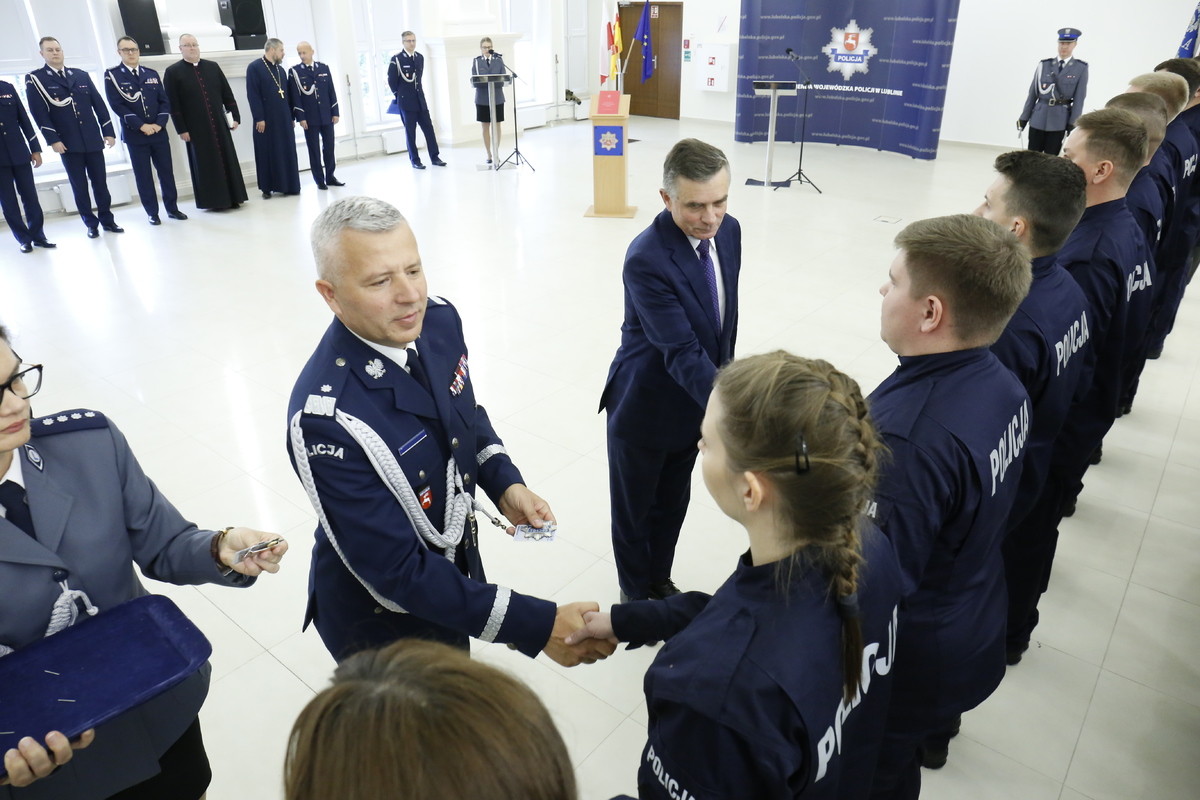 Komendant Wojewódzki Policji w Lublinie nadinsp. Artur Bielecki wraz z Wojewodą Lubelskim Lechem Sprawką wręcza legitymacje nowym funkcjonariuszom.