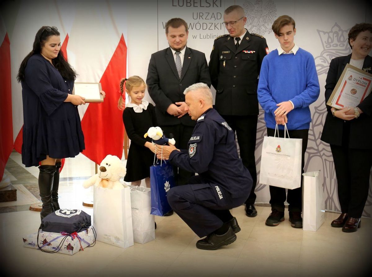 komendant wręcza upominek dziewczynce, która uratowała swoją mamę