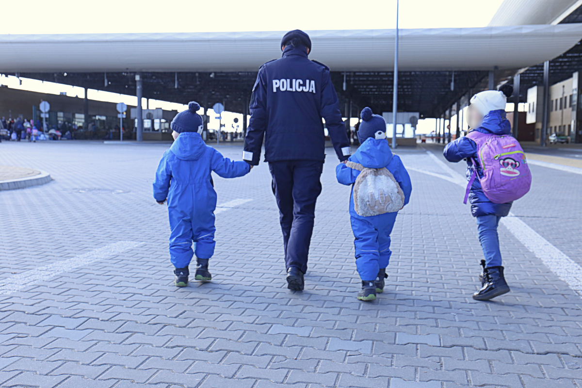Umundurowana policjantka z dziecmi na przejściu granicznym w Dołhobyczowie.