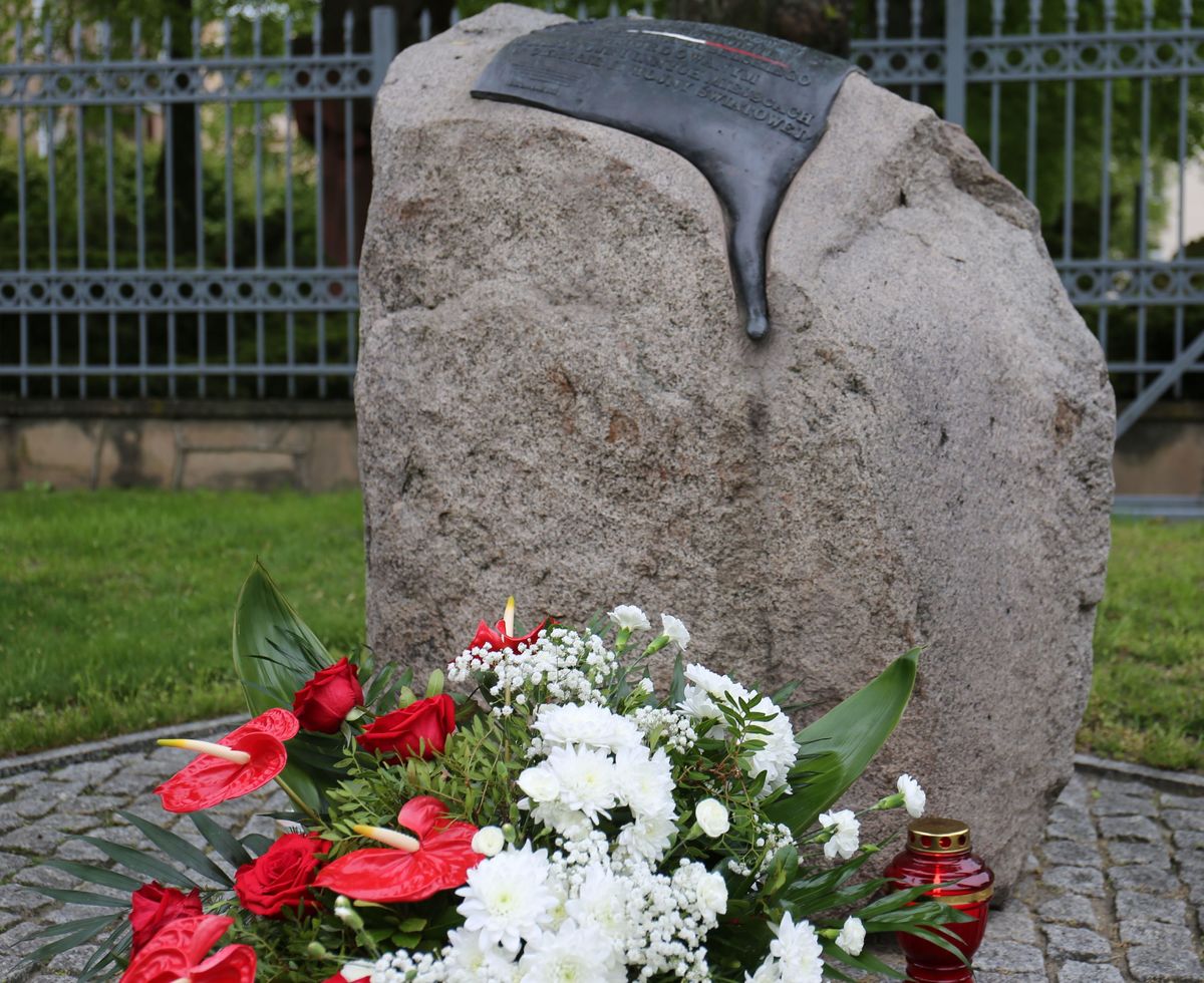 pomnik ofiar funkcjonariuszy z czasów Drugiej Wojny Światowej a przed nim złożona wiązanka