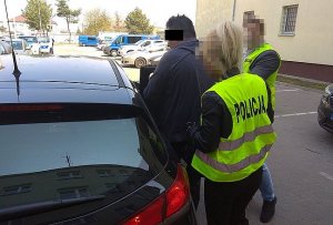 sprawca w asyście policjantów