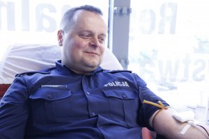 Policjant oddaje krew uśmiecha się.