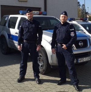 policjanci uczestniczący w akcji , stoją przy radiowozie