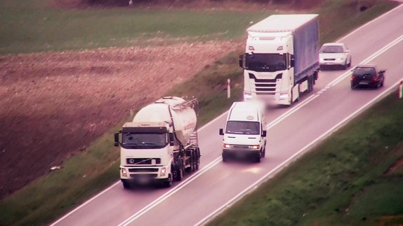 Ujęcie z drona na którym widać busa wyprzedzającego ciężarówkę w miejscu niedozwolonym.