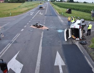 miejsce wypadku, skrzyżowanie, na jego środku leży motocykl i auto leżące na boku