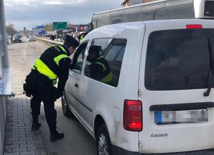 policjant kontroluje biały pojazd na granicy