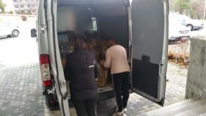 dwie kobiety wypakowują dary z busa