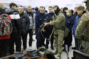 Policjant prezentuje zwiedzającym broń służbową.