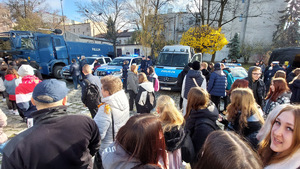 Na zdjęciu widzimy młodzież oglądającą oznakowane radiowozy policji.