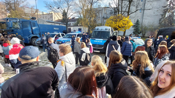 Na zdjęciu widzimy młodzież oglądającą oznakowane radiowozy policji.