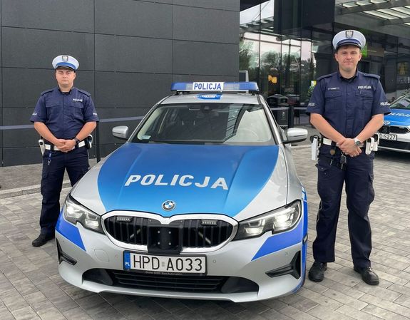 policjanci stojący przy radiowozie