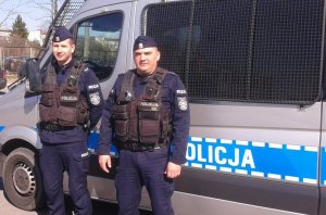 Na tle pojazdu służbowego policjanci z białostockiego oddziału prewencji, którzy udzielili pomocy młodej kobiecie. Funkcjonariusze zadbali o jej bezpieczeństwo do chwili przyjazdu karetki pogotowia, która przetransportowała poszkodowaną do szpitala.