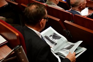 jeden z mężczyzn, uczestnik konferencji, czytający gazetę policyjna &quot;magazyn 997&quot;