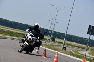 Policjant na motocyklu przejeżdża między pachołkami.