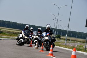 Czterech policjantów jedzie slalomem między pachołkami.