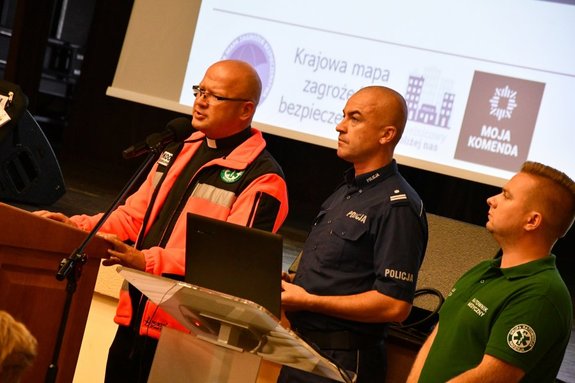 Policjant, ksiądz i ratownik przemawiają na konferencji.