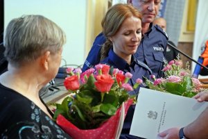 Policjantka i starsza kobieta z kwiatami.