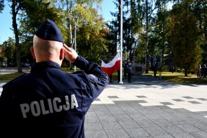 Policjant oddaje honory w trakcie hymnu.