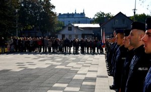 Nowoprzyjęci policjanci. W tle rodziny i znajomi policjantów.