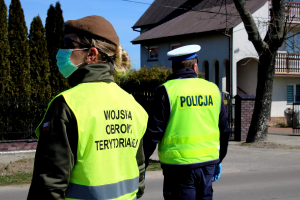 Policjant ruchu drogowego i żołnierz wojsk obrony terytorialnej na drodze.