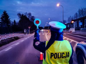 Po zmierzchu policjantka zatrzymuje tarczą pojazd do kontroli.