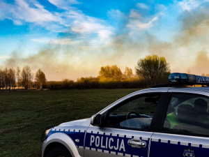 Palące się łąki w Biebrzańskim Parku Narodowym.  Na pierwszym planie radiowóz.