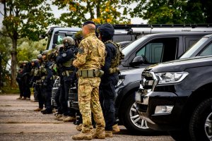 Policjanci stoją przed samochodami.