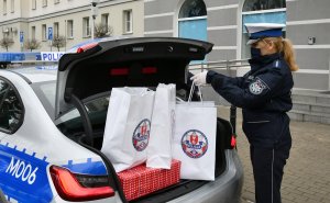 Policjantka pakuje prezenty do bagażnika radiowozu.