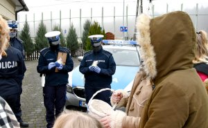 Policjanci trzymają zapakowane ciasteczka,  które otrzymali od dzieci.
