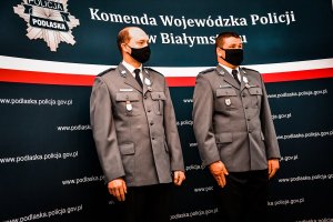 Policjanci stoją przy ścianie z napisami.